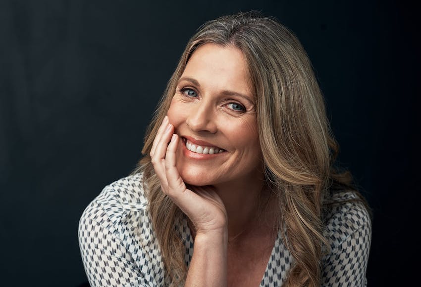 middle aged woman smiling with hand on cheek