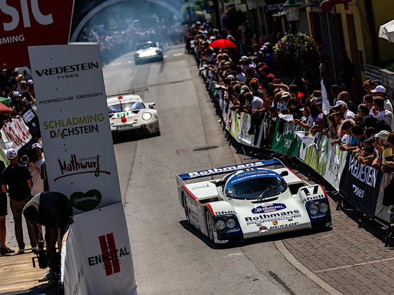 Classic race cars driving through a crowd-lined street at Ennstal-Classic rally — BUBEN&ZORWEG