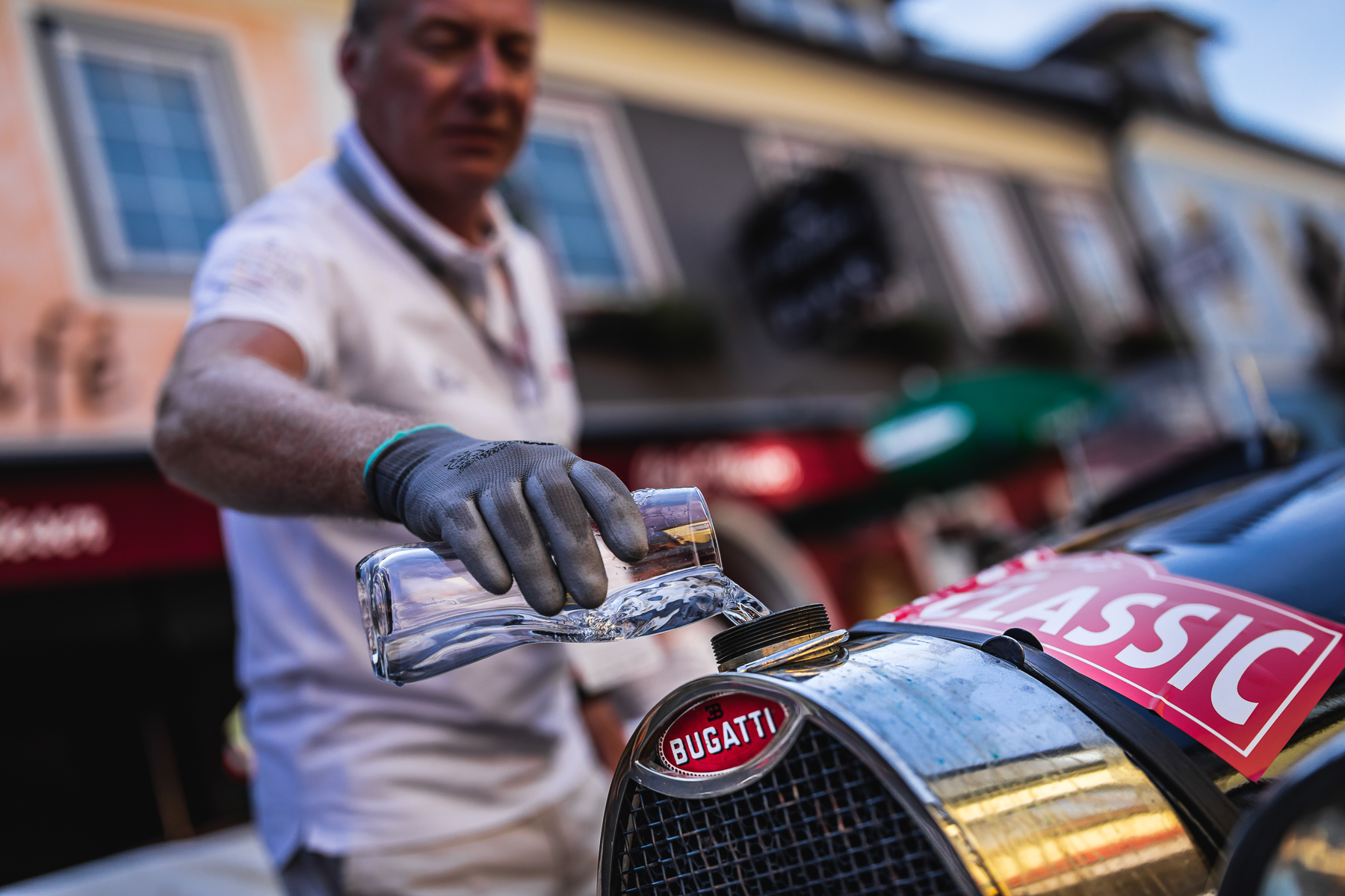 Man pouring water into a classic Bugatti car during Ennstal-Classic rally — BUBEN&ZORWEG