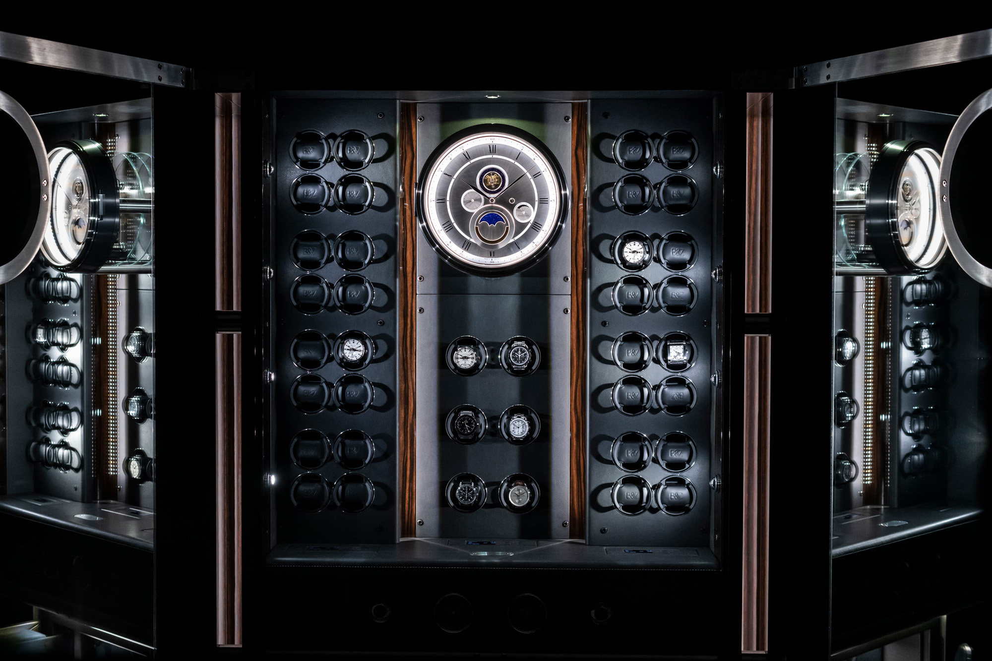 このエレガントな飾り棚に飾られたソリティア独自のインテリアをご覧ください。中央にはローマ数字と見事なムーンフェイズ表示のアナログ時計があります。時計愛好家やコレクターに最適です。 — BUBEN&ZORWEG