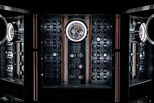 Entdecken Sie unser exklusives SOLITAIRE-Interieur, das in dieser eleganten Vitrine mit einer Analoguhr mit römischen Ziffern und einer beeindruckenden Mondphasenanzeige in der Mitte präsentiert wird. Ideal für Uhrenliebhaber und Sammler. — BUBEN&ZORWEG