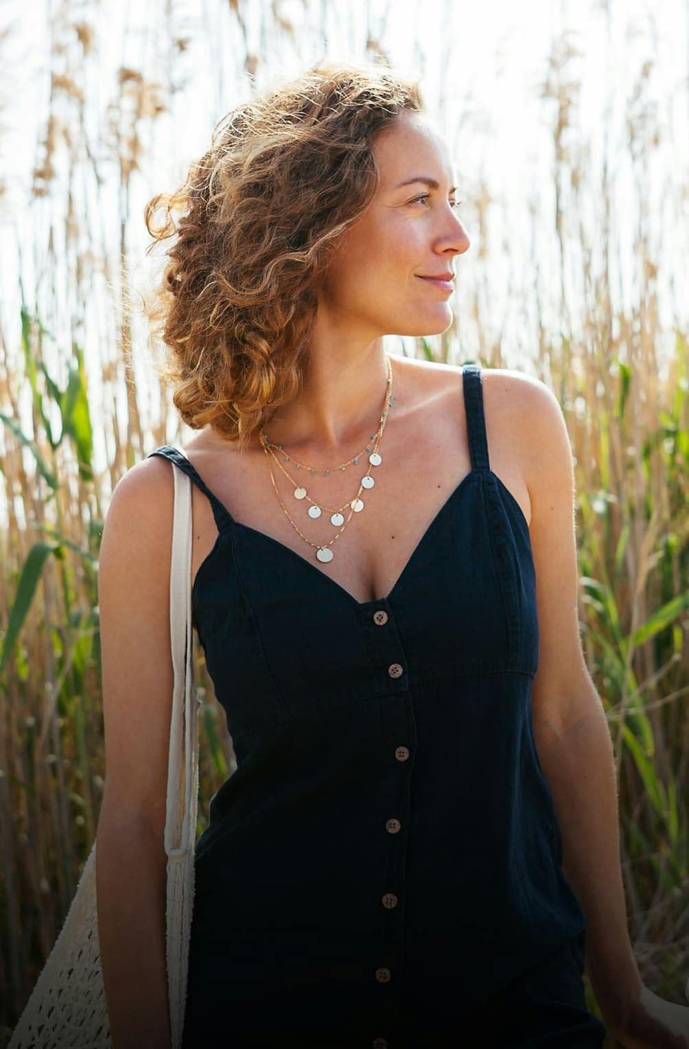 A woman in a dress standing in front of tall grass