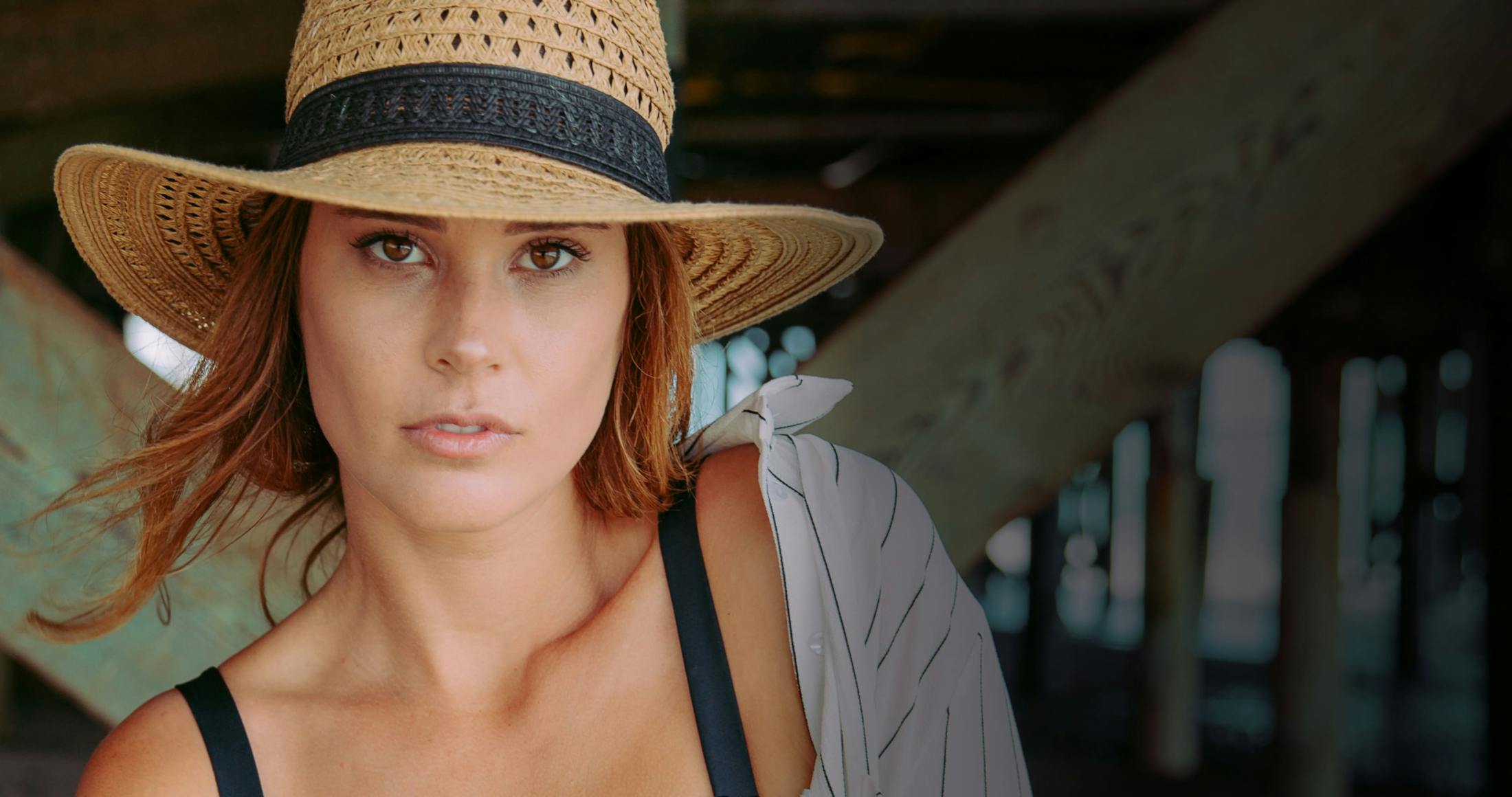 A woman in a summer hat under a dock