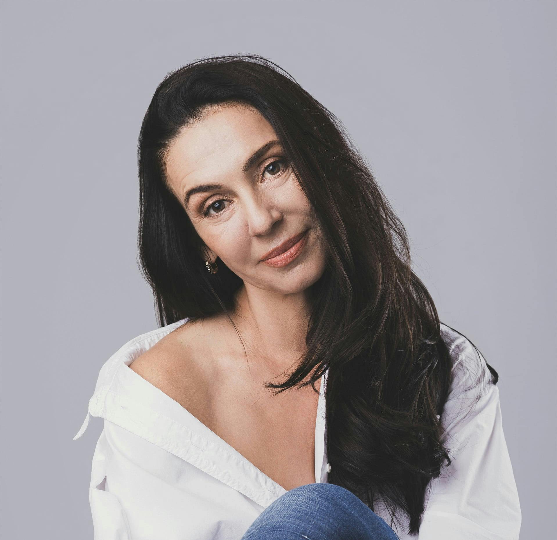 woman with brown hair and a white collared shirt off her shoulder