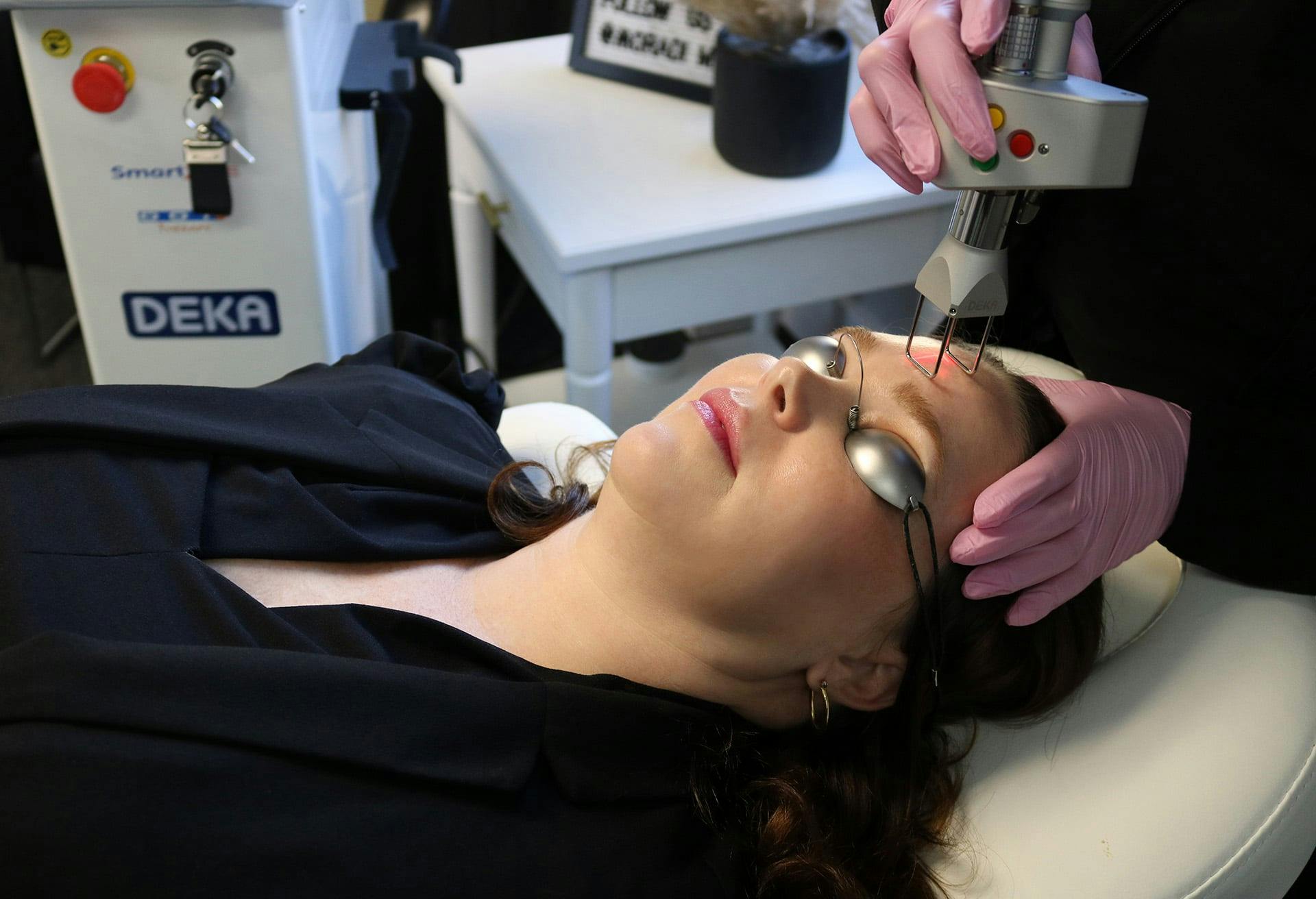 woman laying on the patient chair and a laser device on the skin