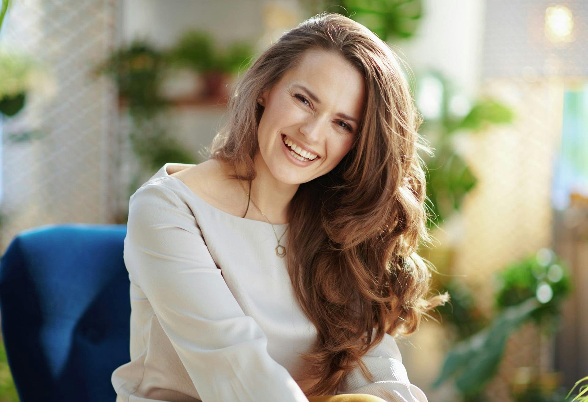 woman with cream colored blouse and brown long hair smiling
