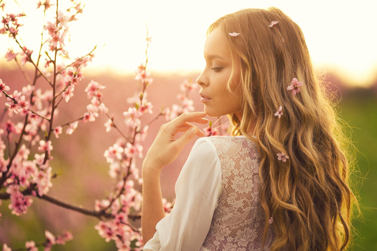 Woman standing by a tree with pink flowers