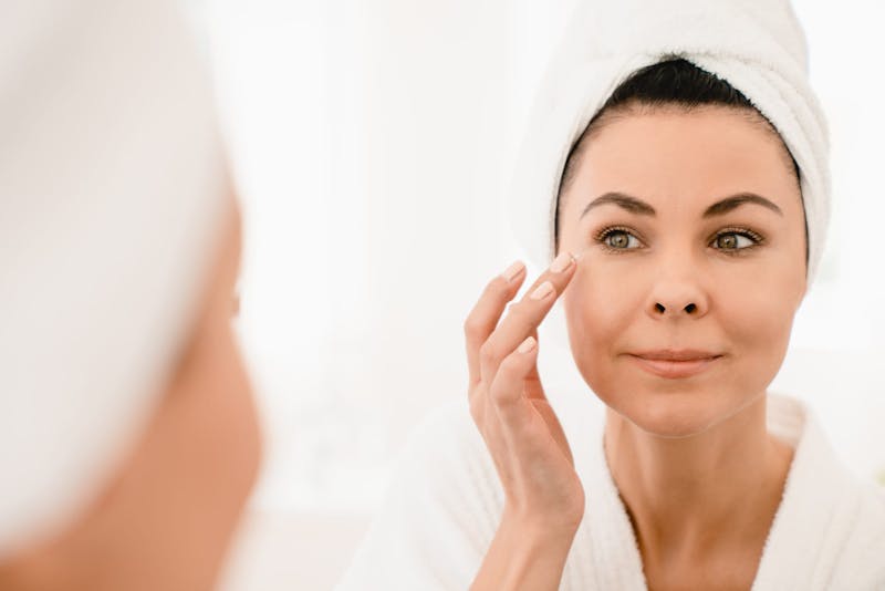 woman examining her eyes in mirror