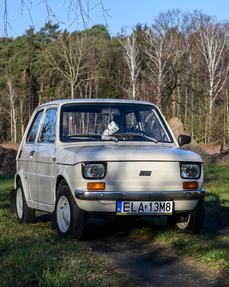 Zdjęcie białego samochodu maluch na polu