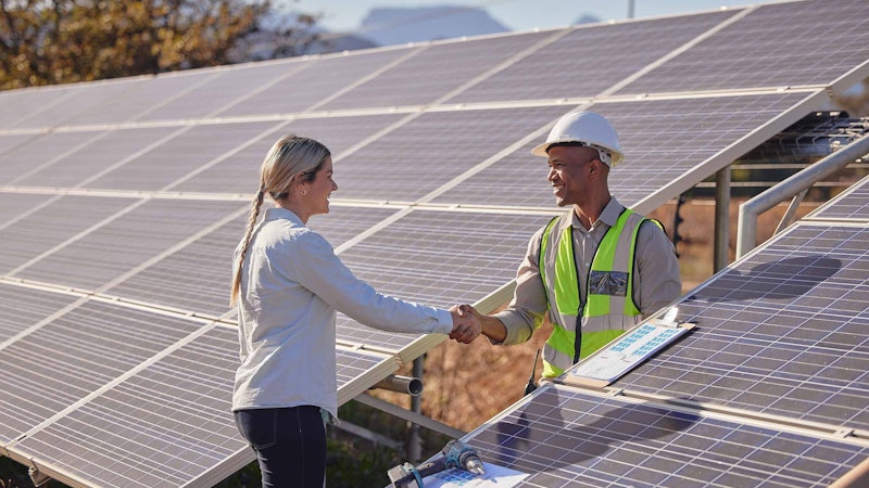 Solar worker shaking hands with a women in a large solar installation.