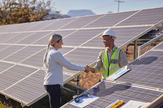 Solar worker shaking hands with a women in a large solar installation.