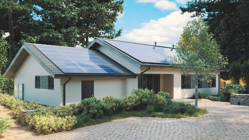 Solar backup for home installed on the roof of a white house in cobble driveway with a blue sky.