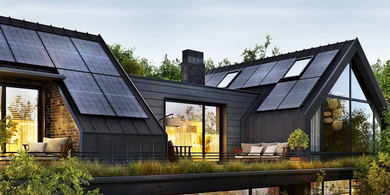 Modern black house with lights on, using solar home energy storage on sharp roofs.