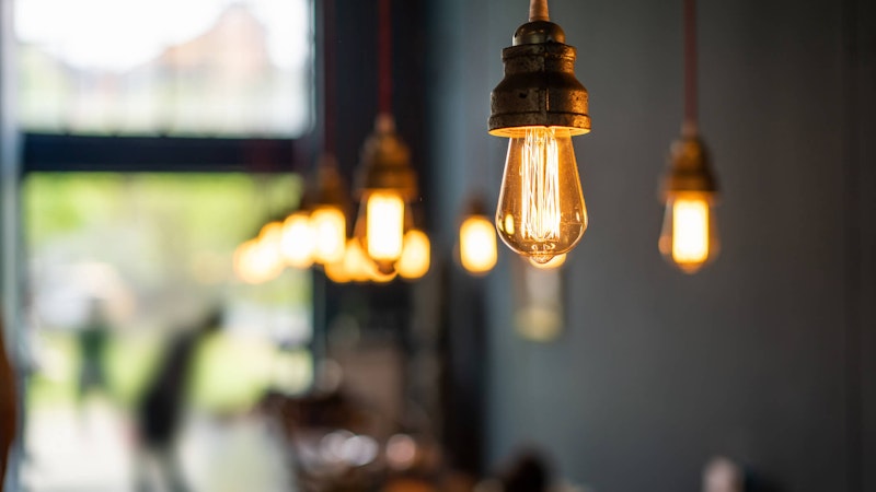 Illuminated light bulbs in a row slowly leaving focus in a coffe shop.