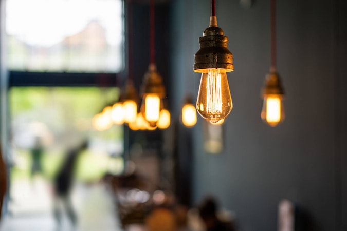 Illuminated light bulbs in a row slowly leaving focus in a coffe shop.