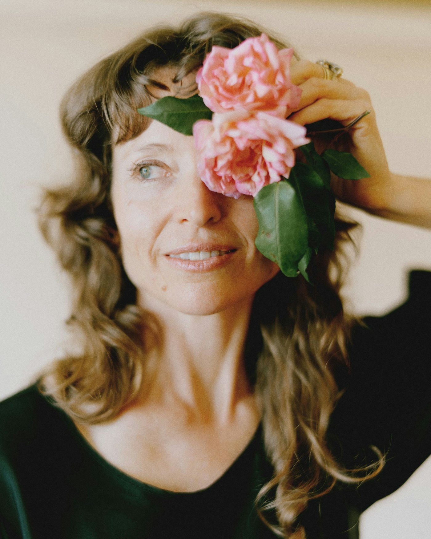 Amber holding a flower in front of one eye and smiling
