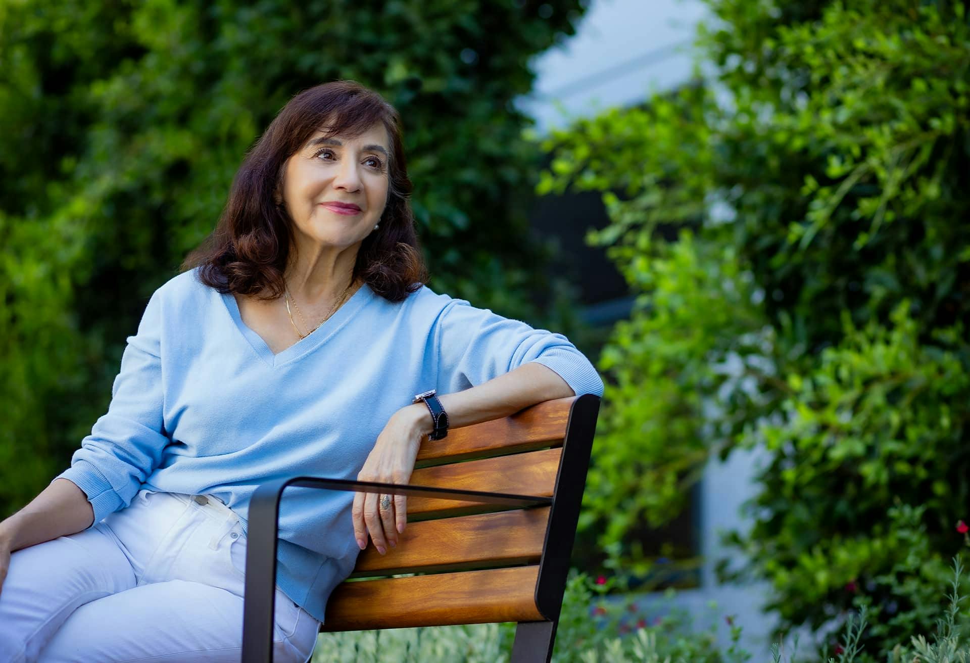 A woman on a bench in a blue sweater looking to side