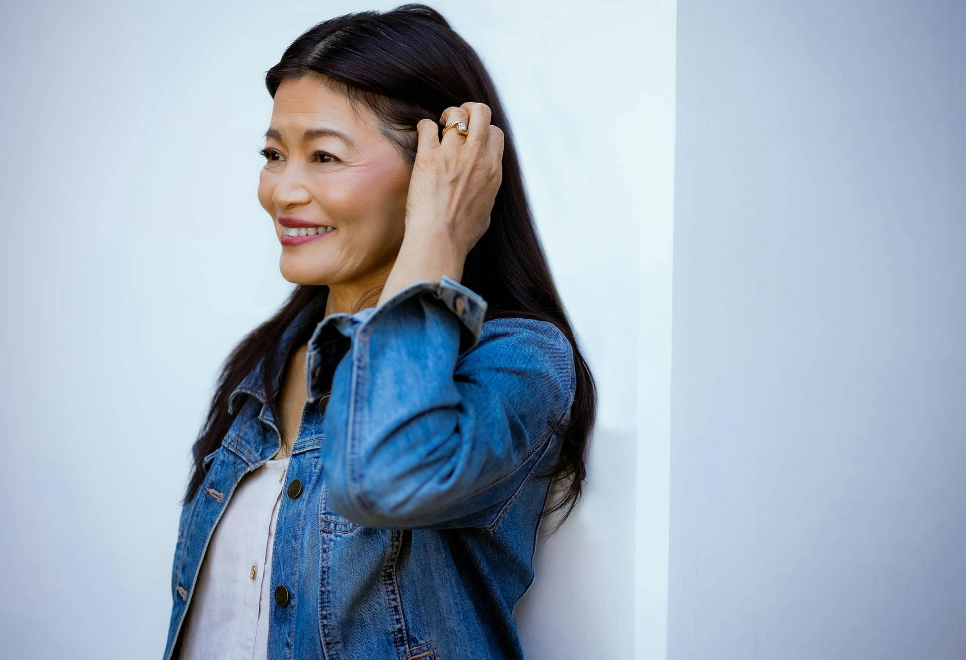 A woman in a jean jacket touching her hair