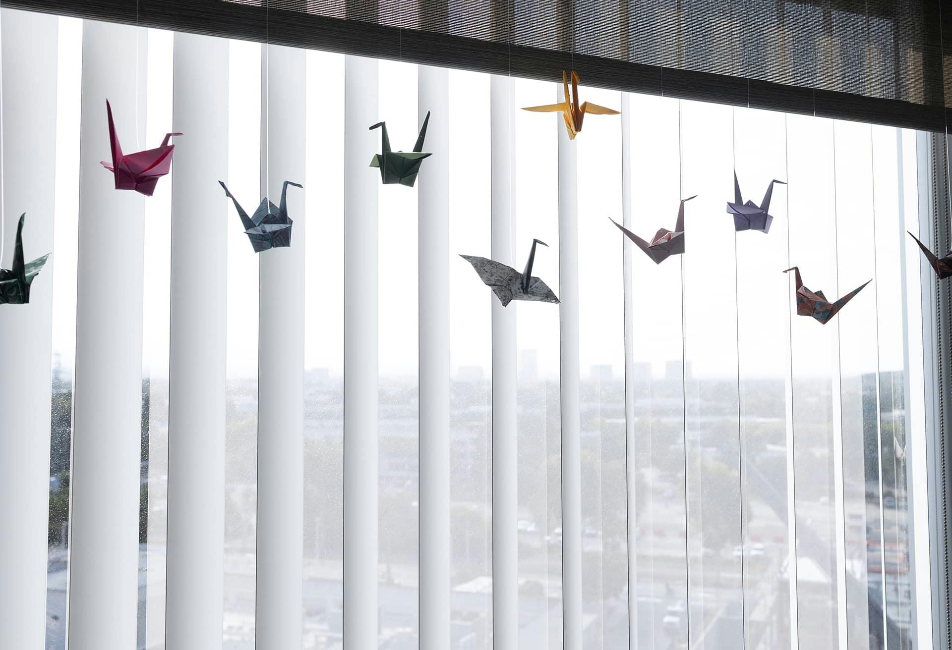 Birds made out of paper in front of a window