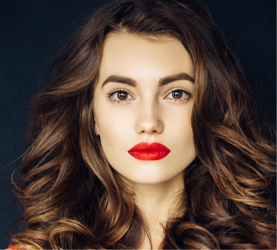 Woman with big curly brown hair and red lipstick on