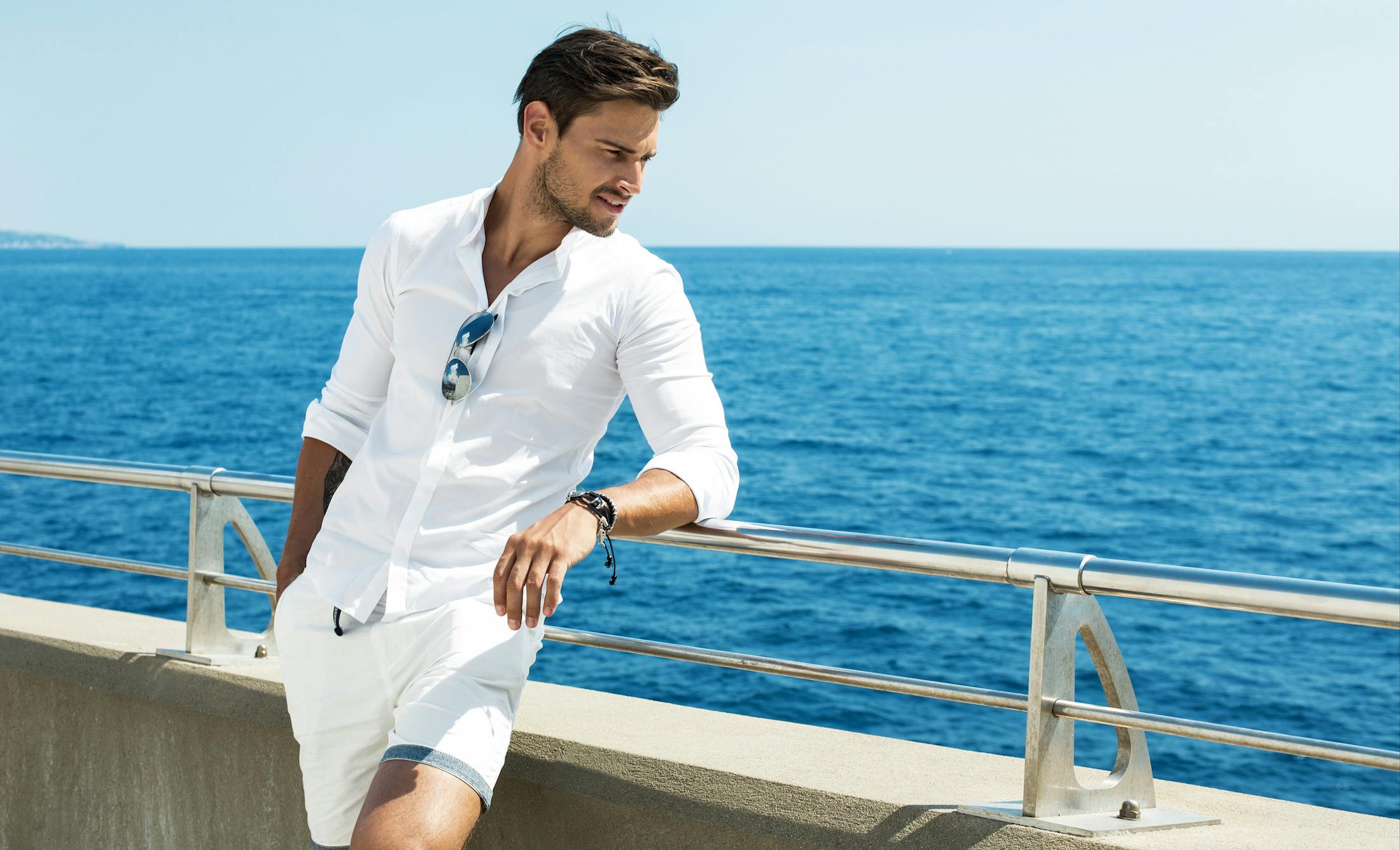 man leaning on railing by water
