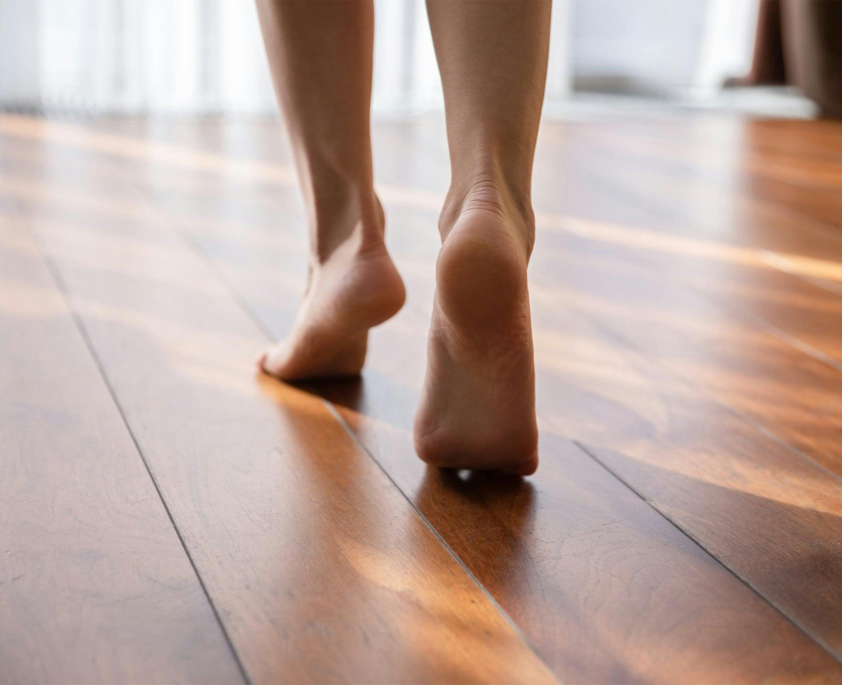 Woman standing on her toes on a hardwood floor