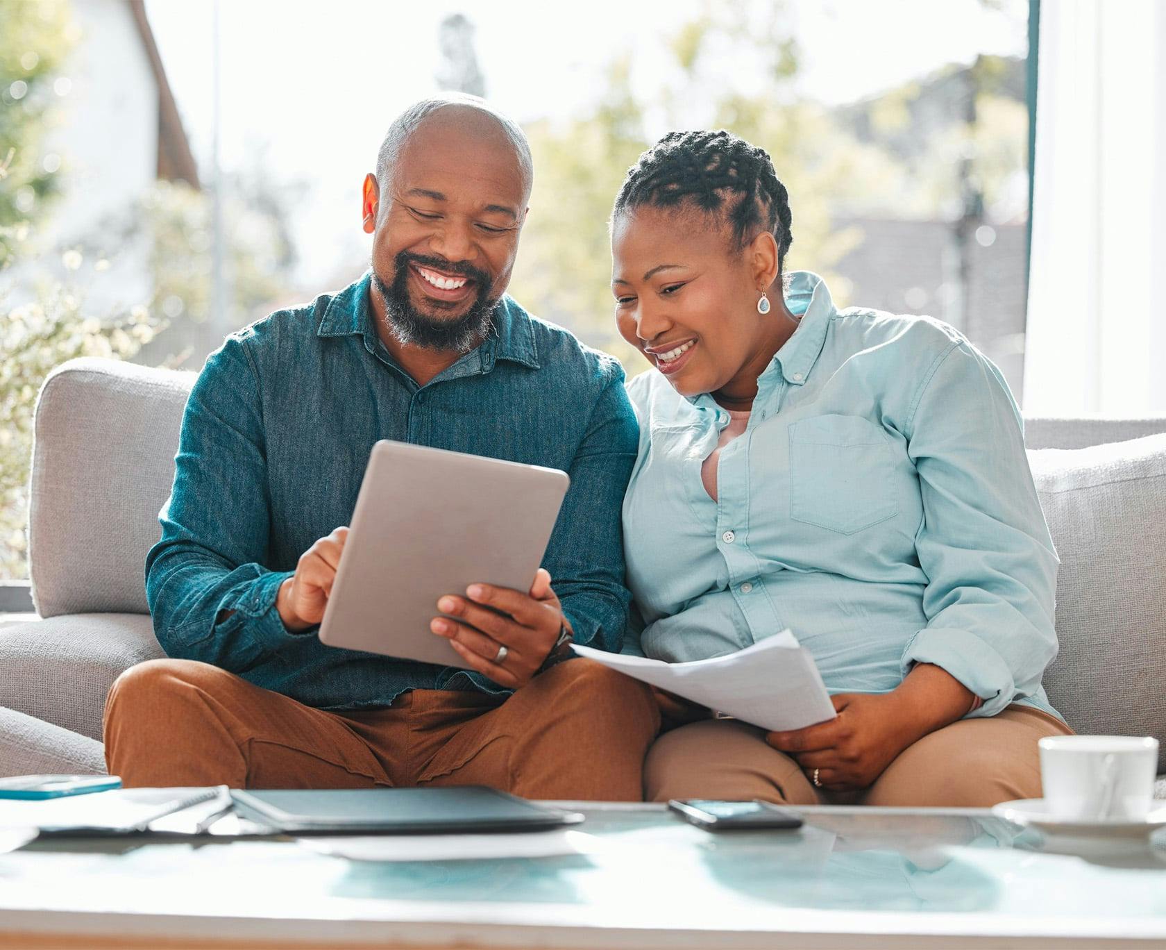 Man and woman sitting on a couch looking at an ipad