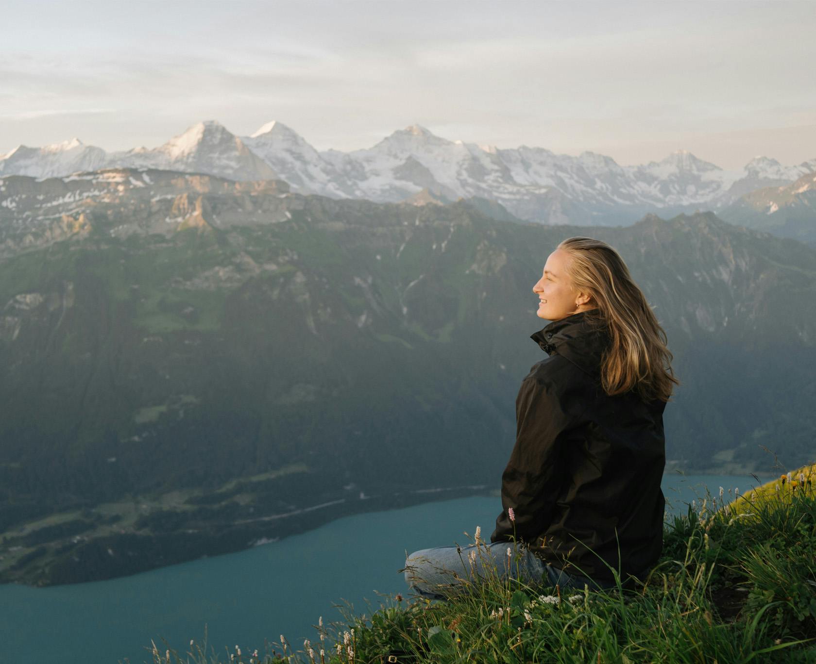Woman sitting on a mountain overlooking a lake and other mountains