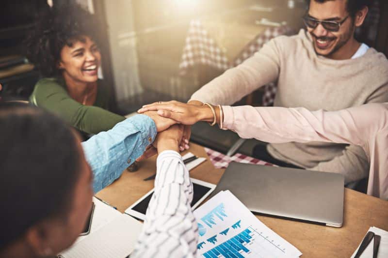 groupes de salariés heureux se tenant les mains et faisant équipe, symbole du bien-être au travail