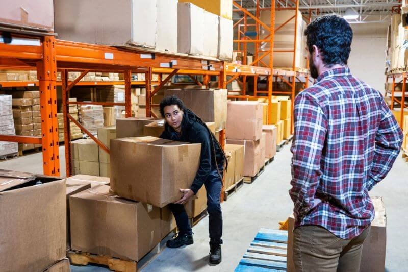 Formateur PRAP conseillant un salarié en train de soulever un carton dans le cadre d'une formation préventions des risques professionnels.