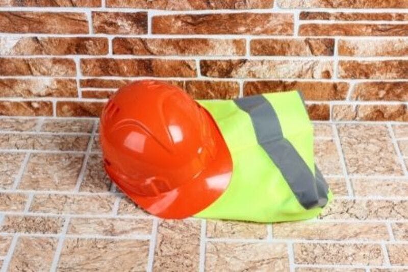 Casque de chantier et gilet de sécurité posés au sol représentant l'équipement nécessaire pour les responsables de la prévention des risques incendie électrique en entreprise