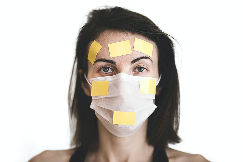 Femme recouverte de post it et d'un masque anti-covid pour symboliser la nouvelle réglementation secourisme liée au covid-19