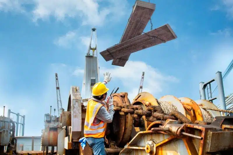 ouvriers en BTP sous des planches soulevées dans les airs au dessus de leurs têtes, pour illustrer la notion de danger au travail