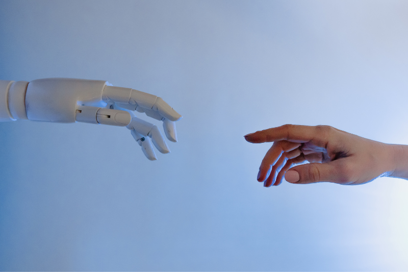 main robotique et main humaine se rencontrant pour symboliser l'aide que peut apporter l'IA à la santé humaine