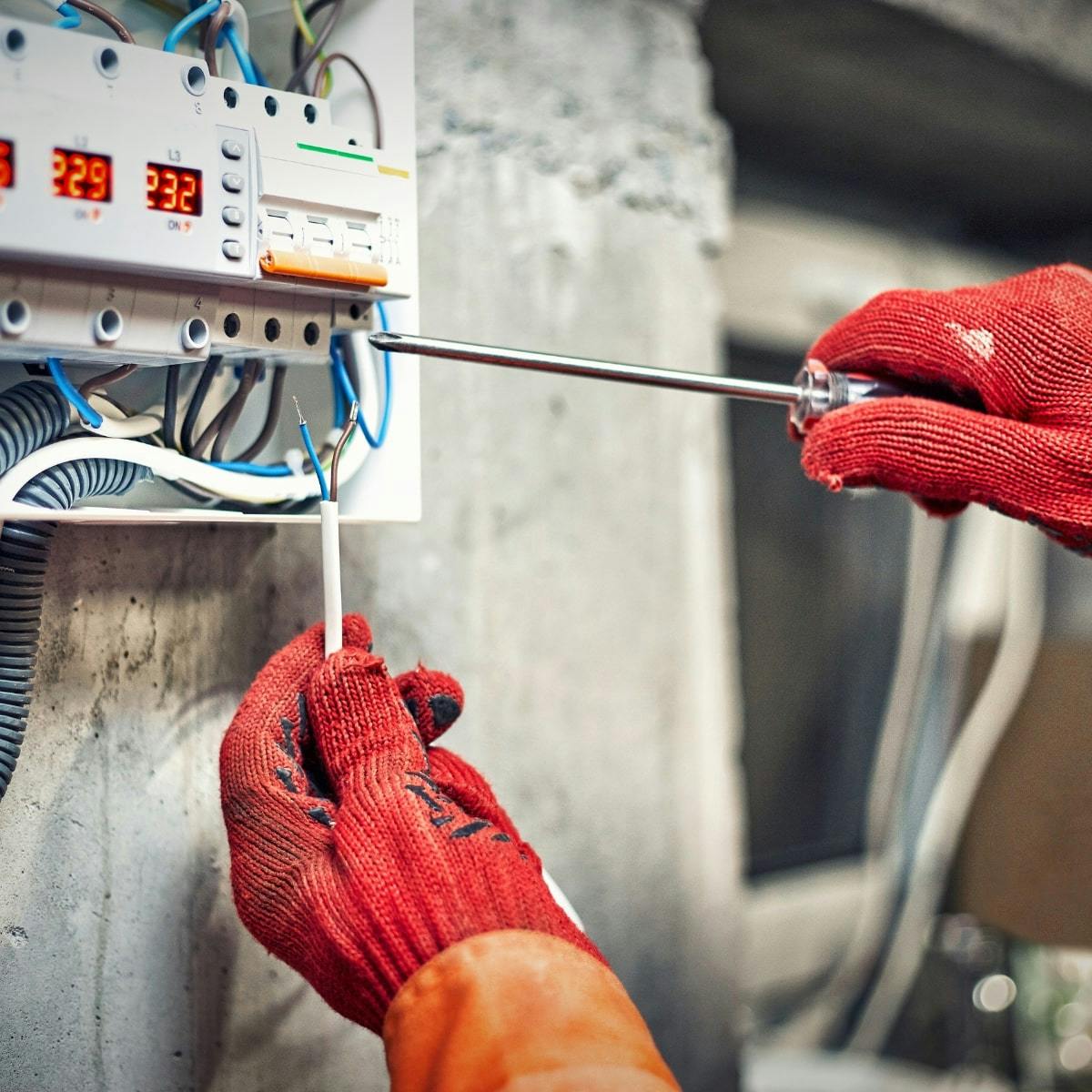 personne intervenant sur un compteur électrique avec des gants de sécurité