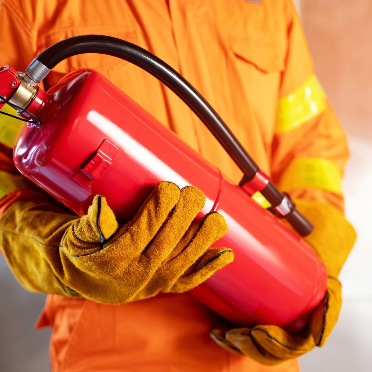 personnel portant un extincteur et vêtu d'une combinaison protectrice contre les incendies pour illustrer des formations non obligatoires en entreprise mais fortement recommandées