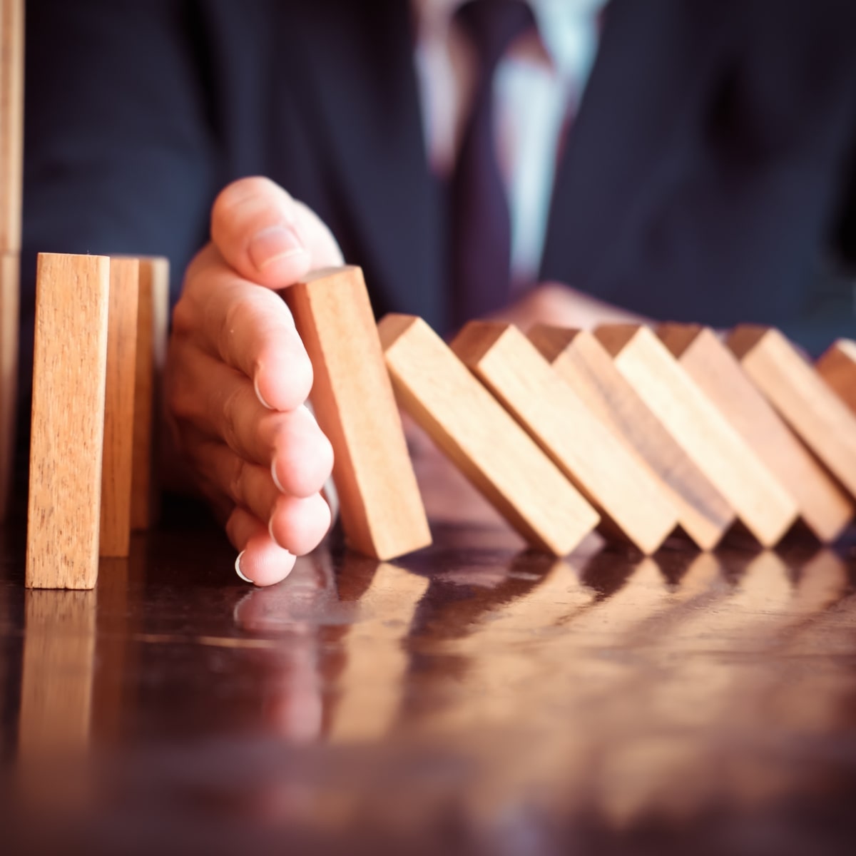 image de domino dont la chute est retenue par une main pour illustrer l'impact positif de la formation PRAP sur la performance de l'entreprise