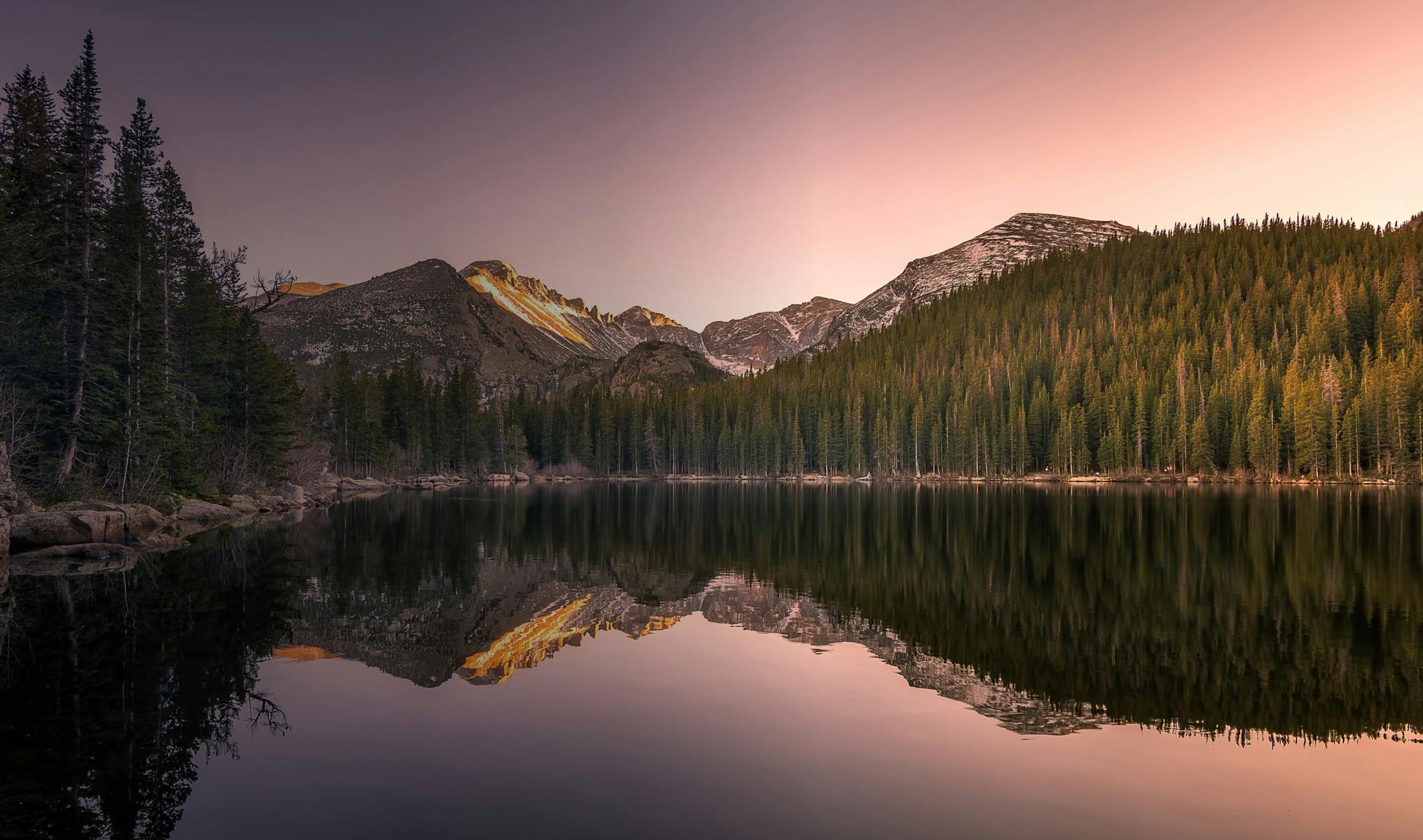 mountains reflected in a lake at sunset with a pink sky