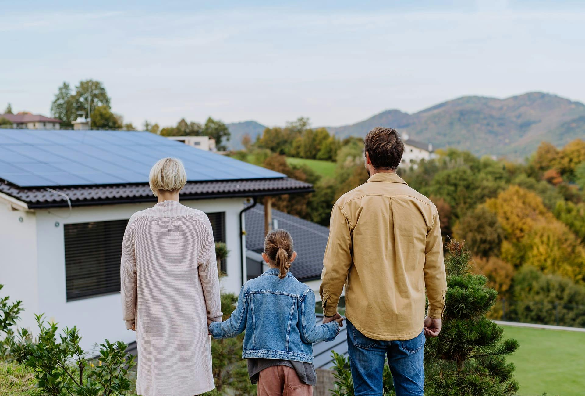 family walking up a hill towards a house with solar panels on the roof