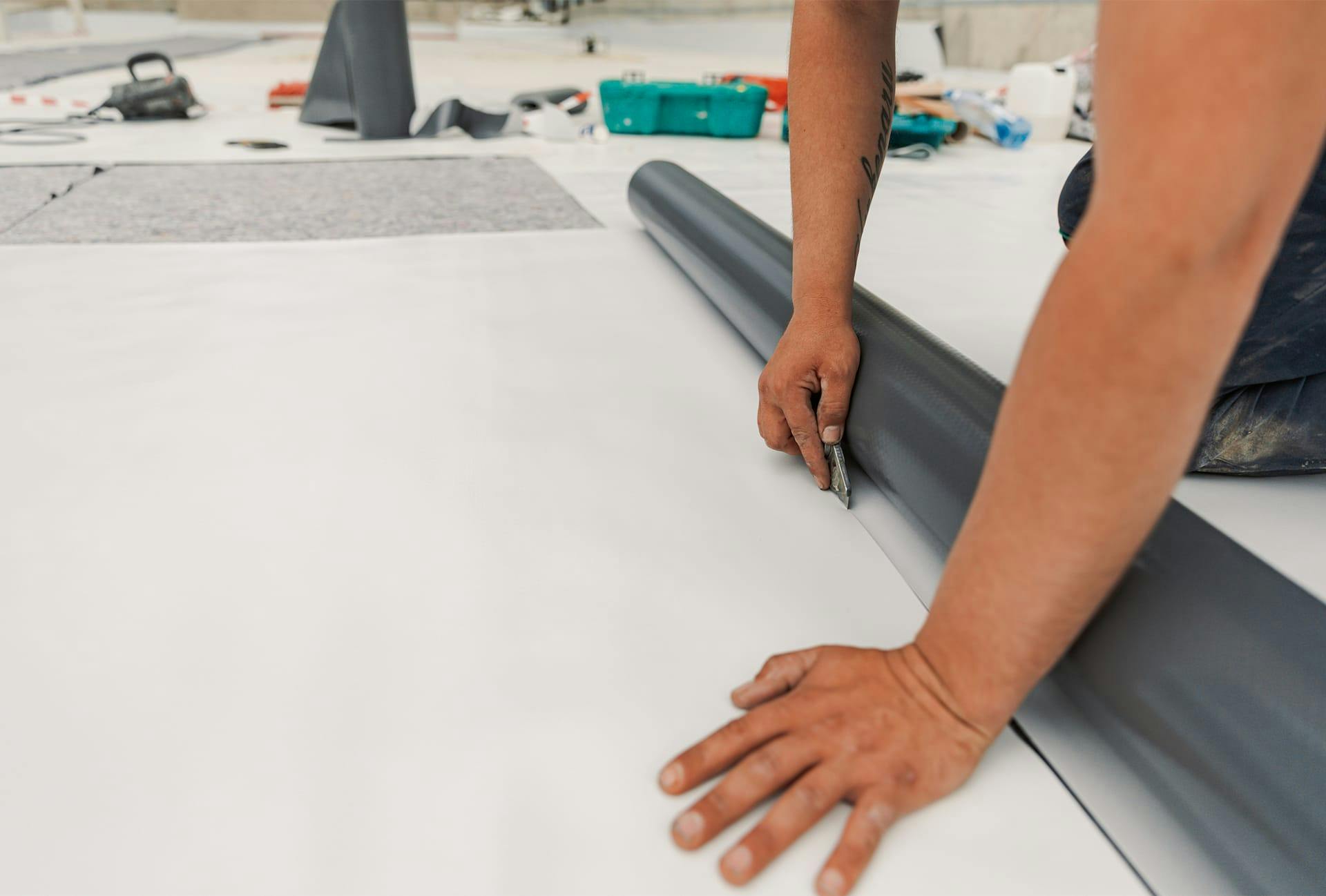 man laying a roll of vinyl on a floor