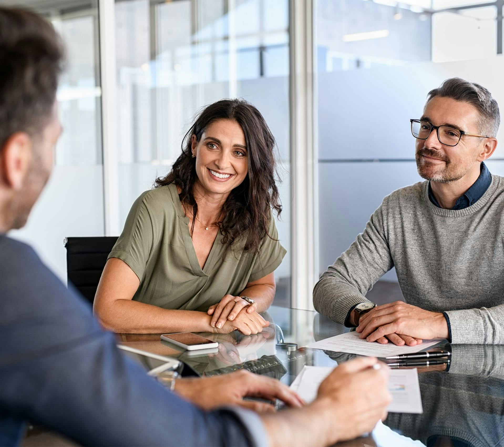 smiling couple sitting at a table with papers and papers in front of them