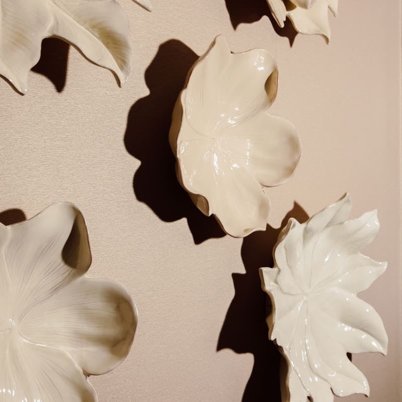 four white flower dishes on the wall next to each other