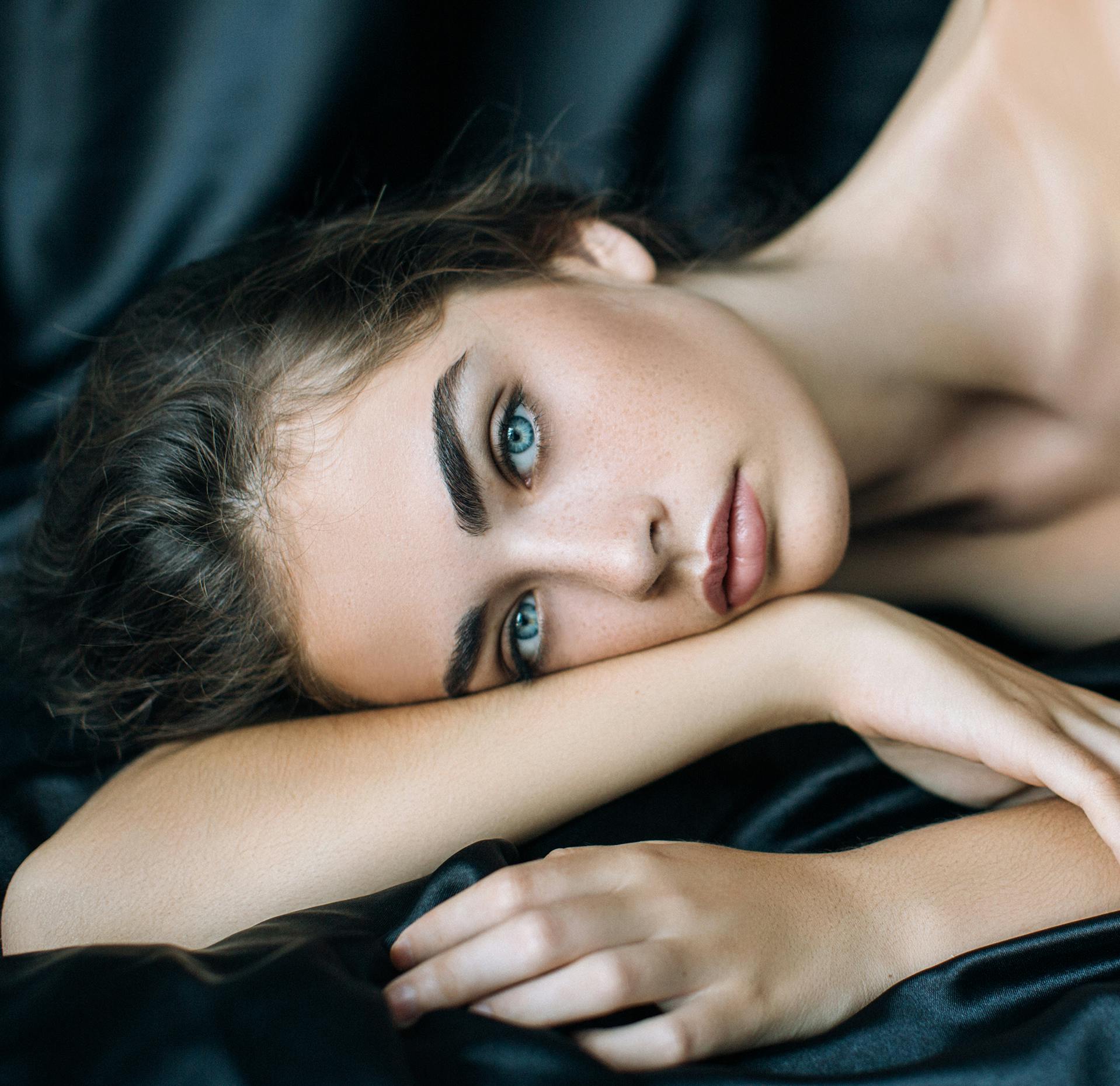 close up of a woman laying on a bed with head on her arms