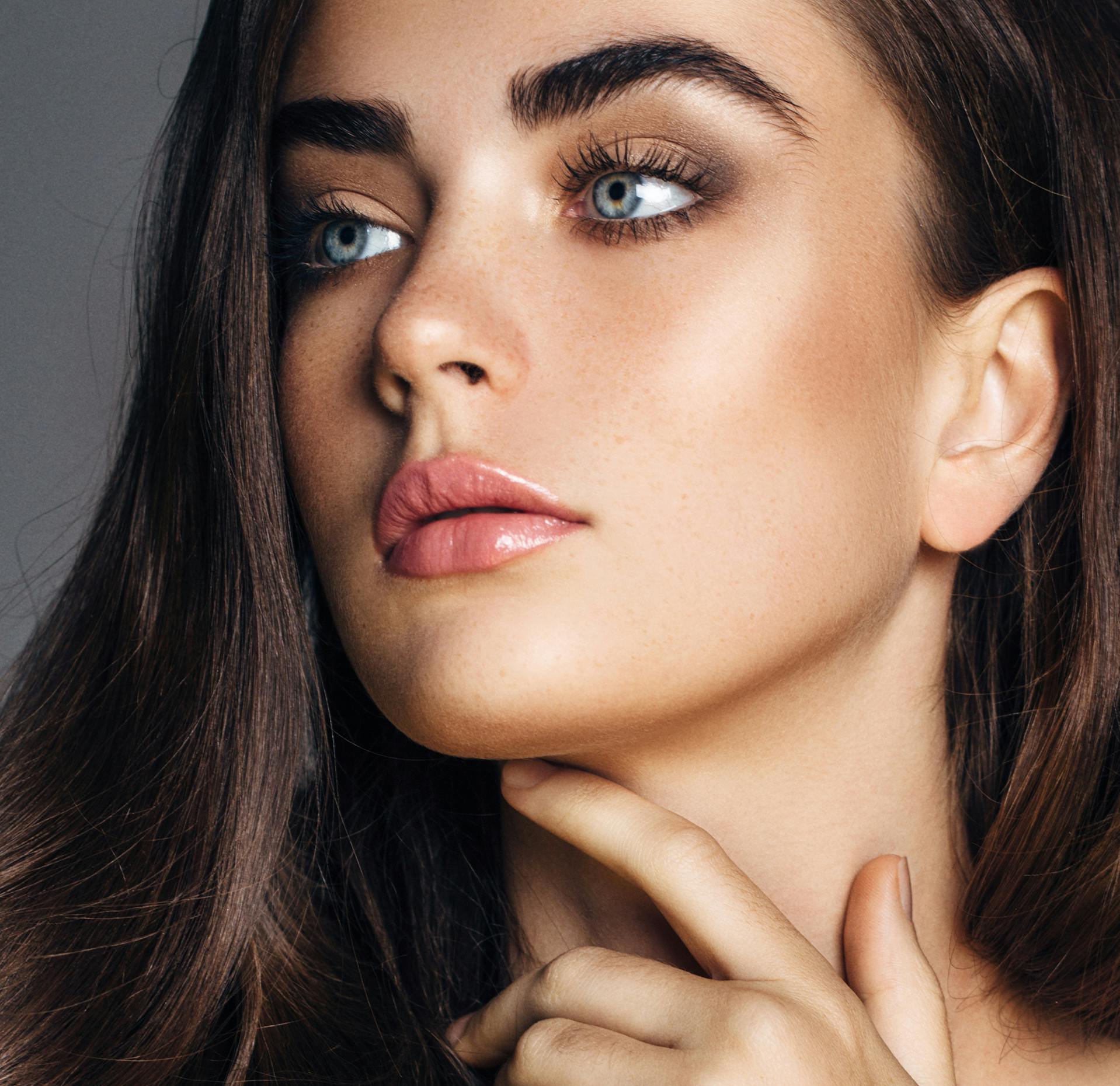 close up of a woman with long hair and a ring on her finger posing for picture