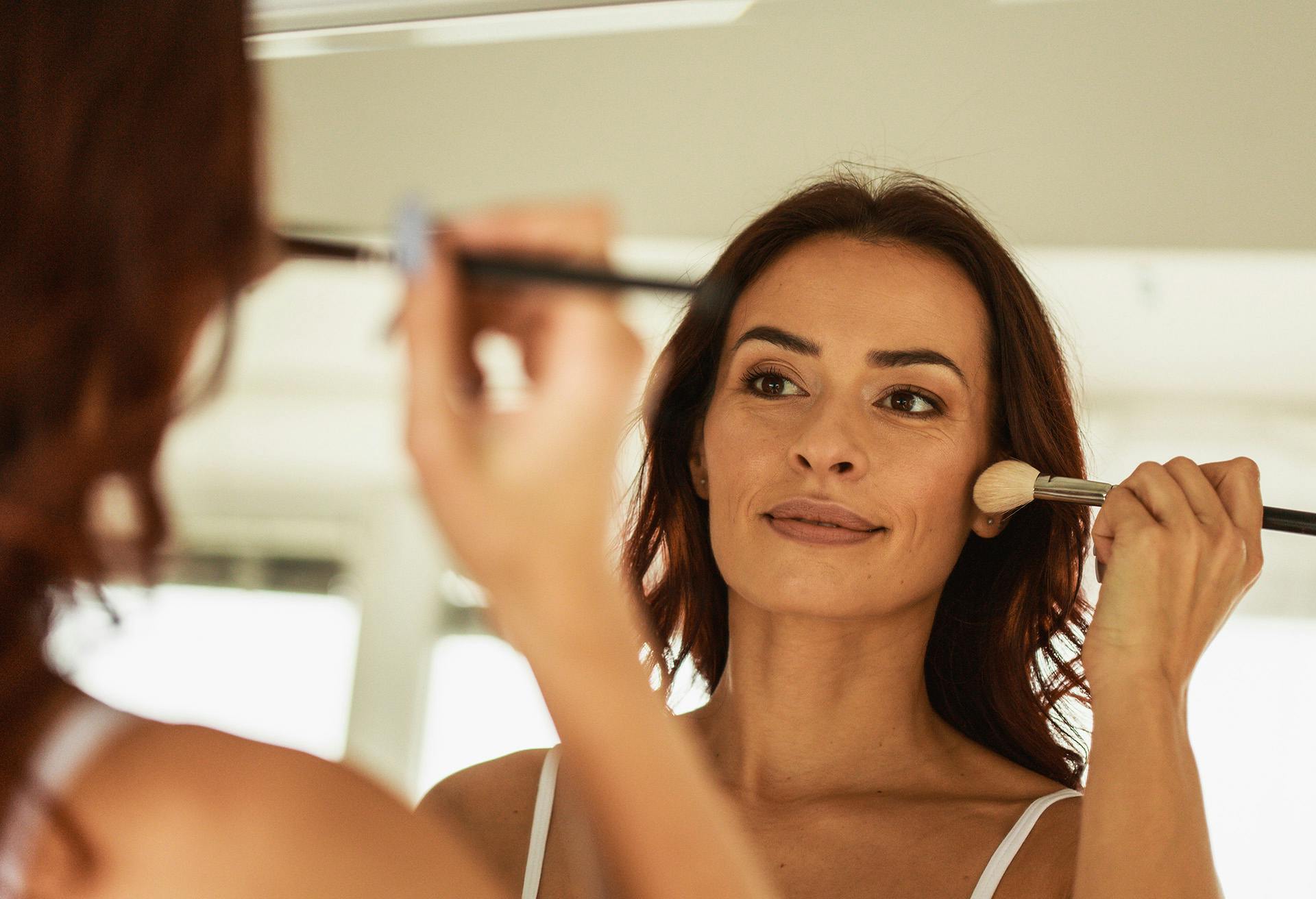 Woman doing her makeup in a mirror