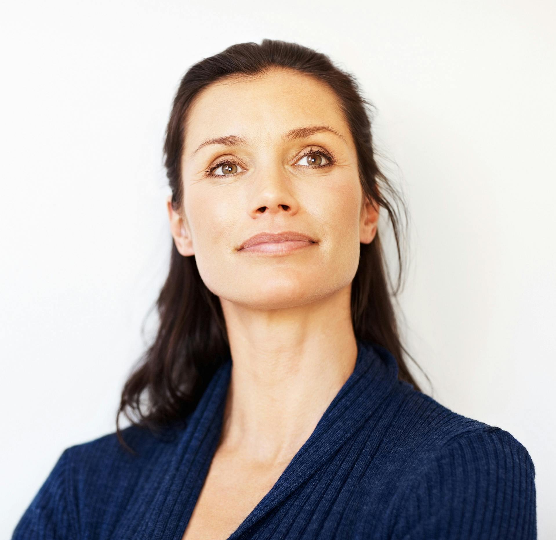 close up of a woman in a blue sweater looking up at the sky