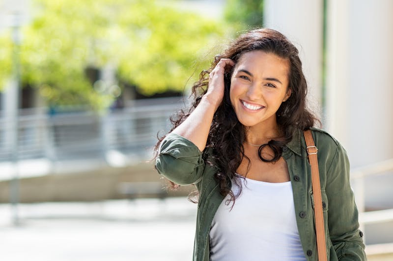 happy woman outside on sunny day with white shirt and olive shirt