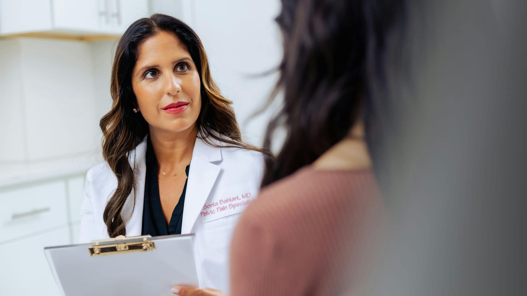 Dr. Sonia Bahlani Holding clipboard speaking with patient
