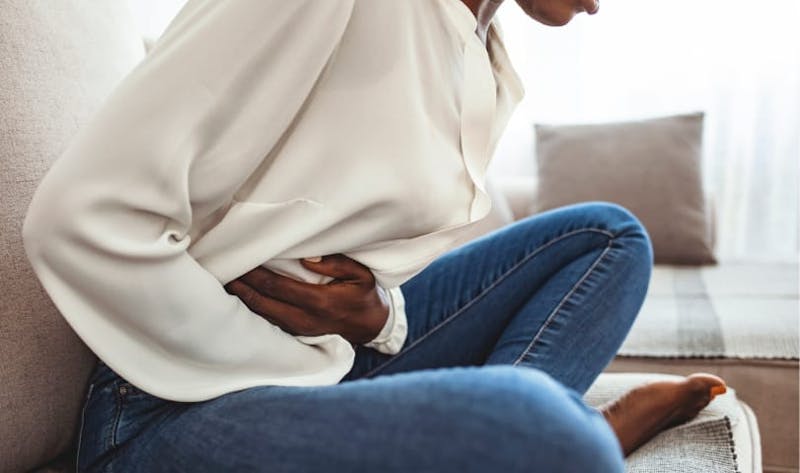 A woman sitting on a couch with abdominal pain