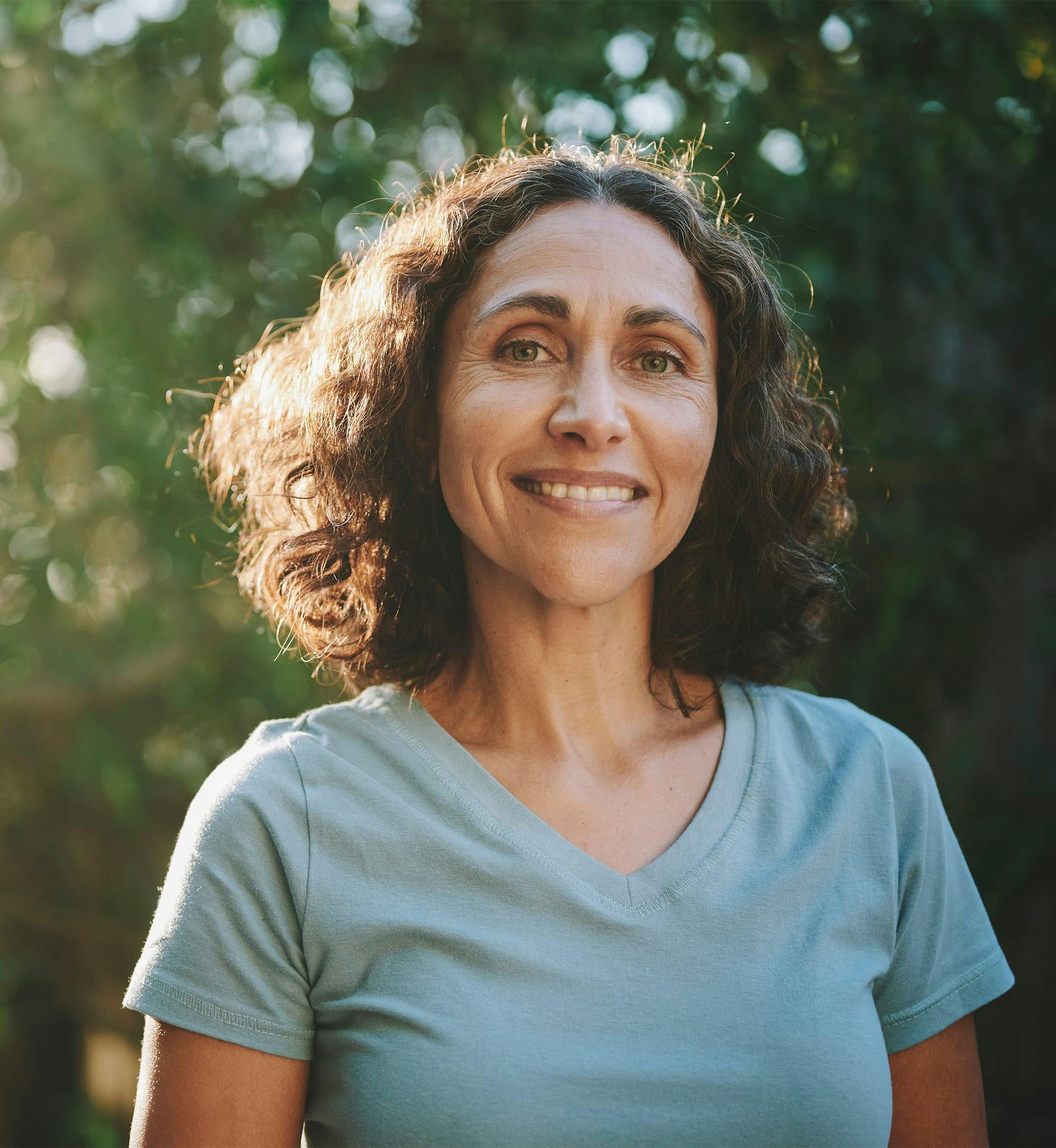 A woman in blue shirt smiling outside